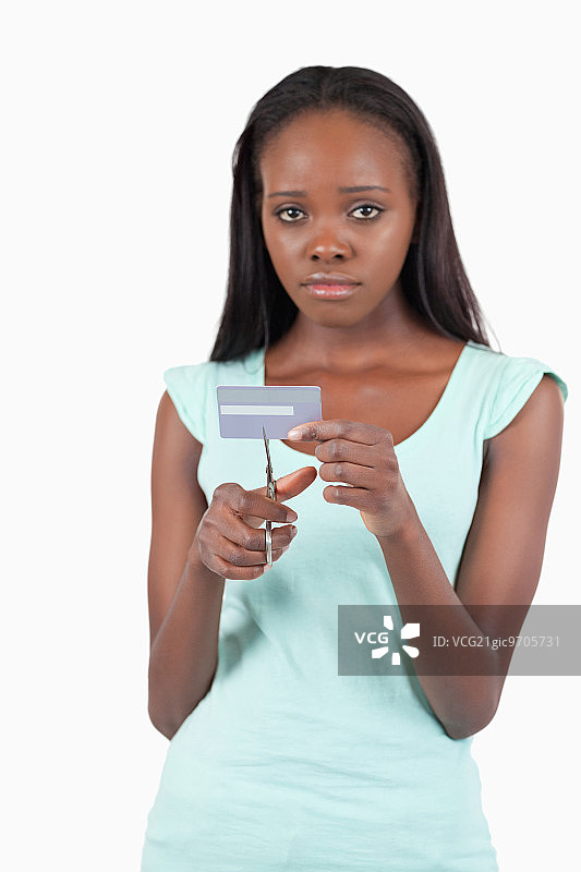 在白色背景下将信用卡剪成碎片的悲伤女人图片素材