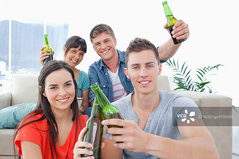 一群快乐的朋友举起酒瓶，开怀畅饮图片素材