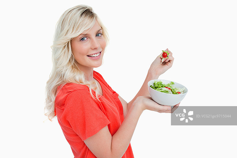 吃着新鲜沙拉，容光焕发的年轻女人的侧面像图片素材