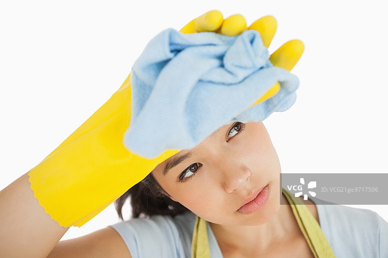 过度劳累的清洁女工擦拭额头，目光移开图片素材