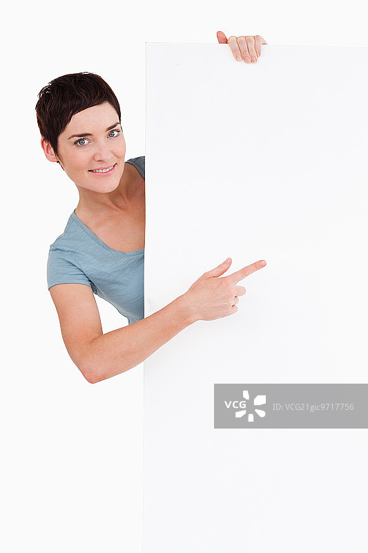 指着白色背景上的空白面板的美丽黑发女人图片素材
