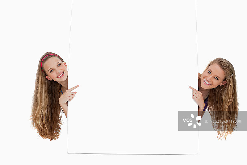 两个长发女人在白色背景前拿着空白标牌的背影图片素材