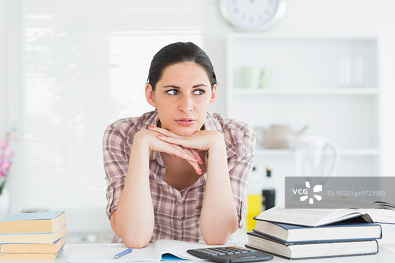 在厨房里用手托着下巴的女人图片素材