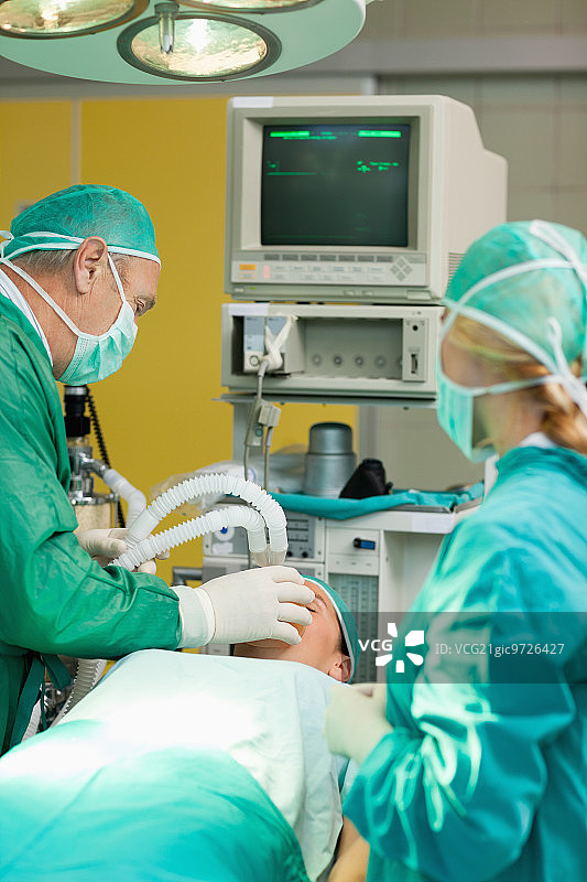 患者躺在手术台上，两位外科医生在手术室里图片素材