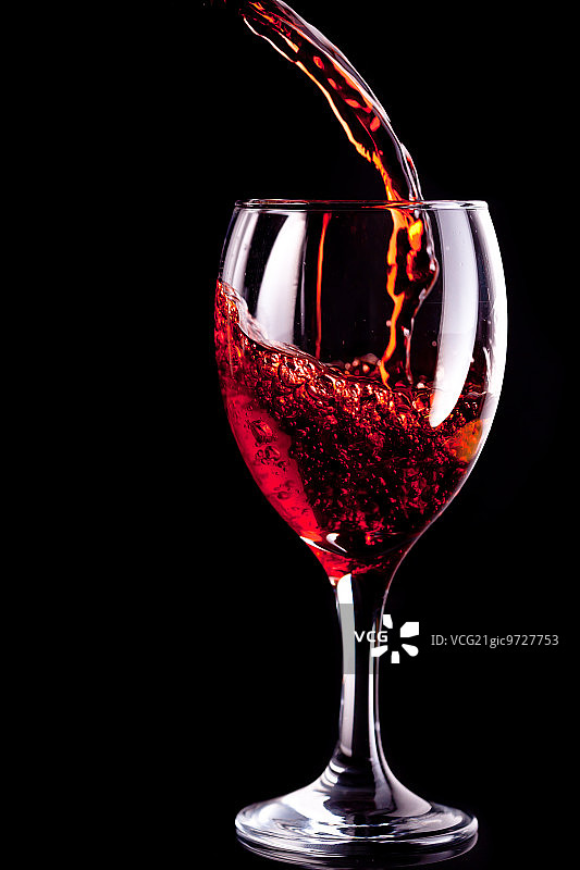 黑色背景下被注满的葡萄酒杯图片素材