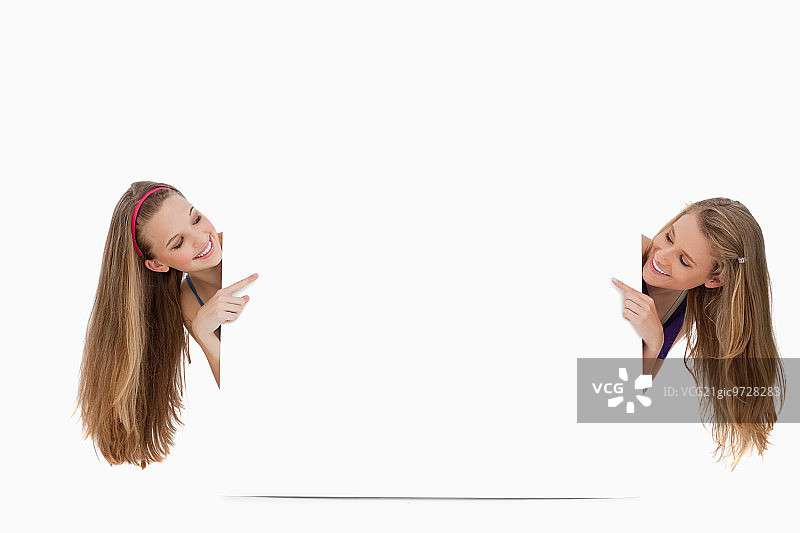 白色背景下一个空白标志后面的两个长发女人图片素材