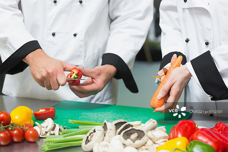 两位厨师在商用厨房准备蔬菜特写图片素材