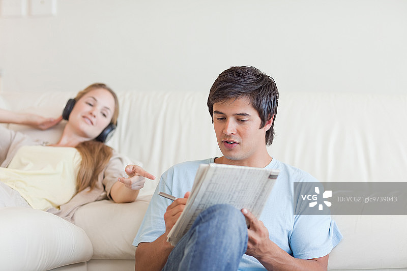 女子在客厅里帮助未婚夫做填字游戏图片素材