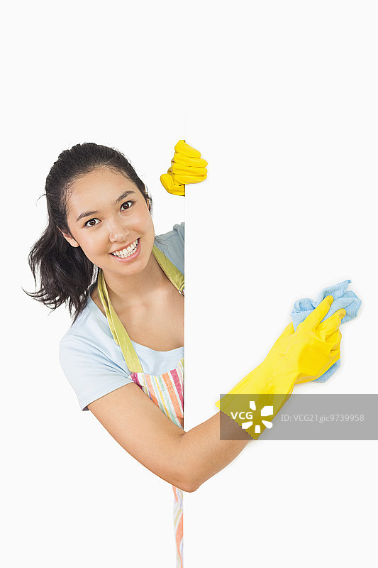 微笑的女人身穿围裙和橡胶手套清洁白色表面图片素材