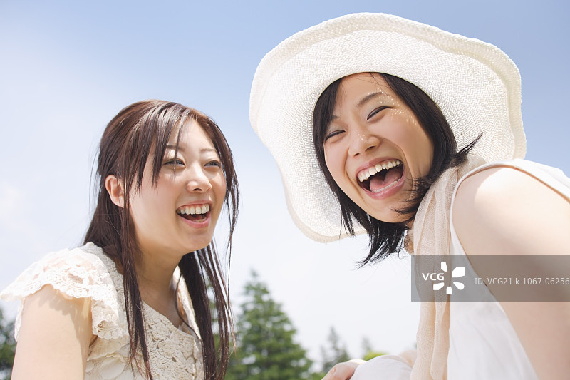 两名对着蓝天微笑的年轻女子图片素材