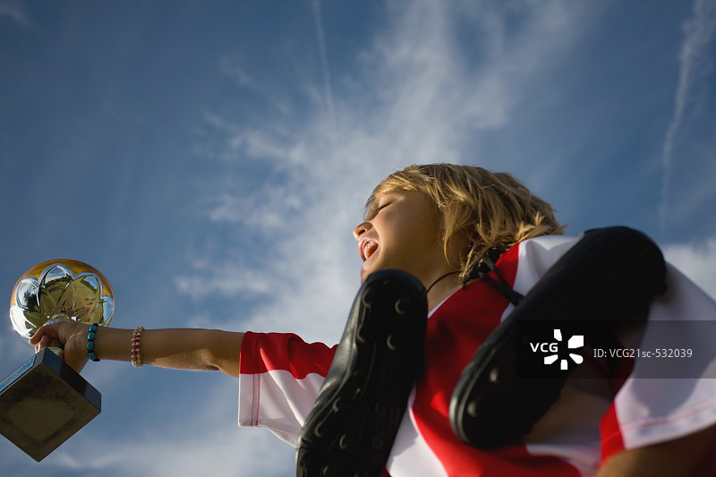 手持球鞋、奖杯并欢呼的足球运动员图片素材