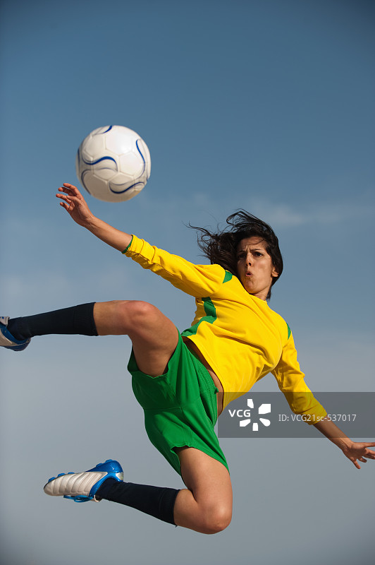 在半空中踢足球的足球运动员图片素材