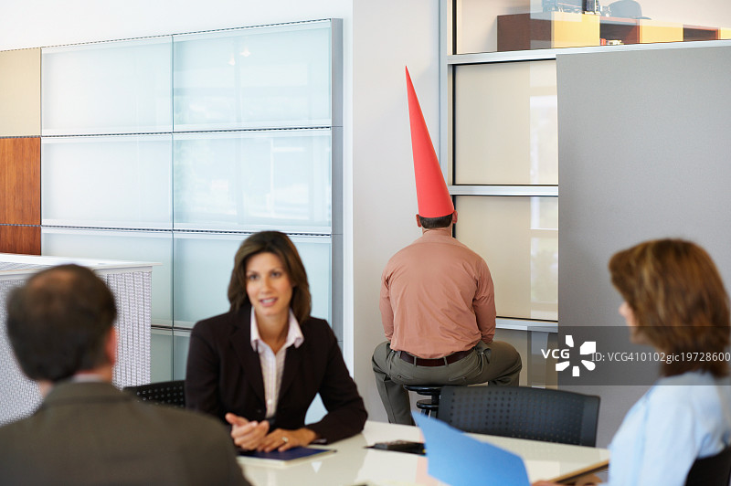 商人戴着一顶蠢帽子坐在角落里图片素材