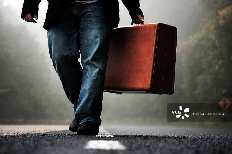 在清晨的雾中拉着行李箱的男人图片素材