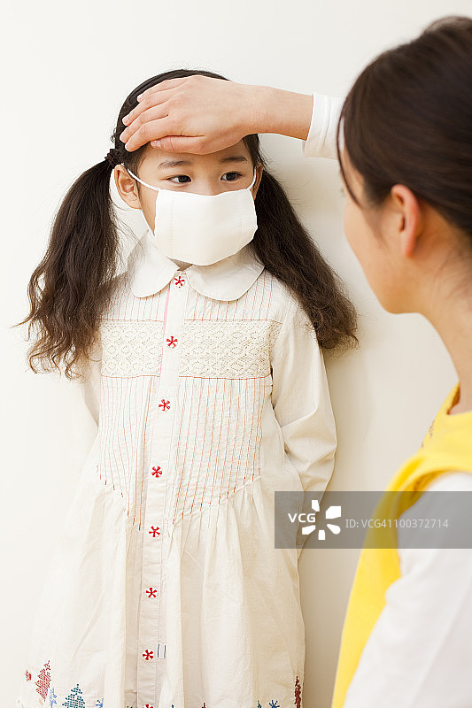 幼儿园老师检查女孩的体温图片素材