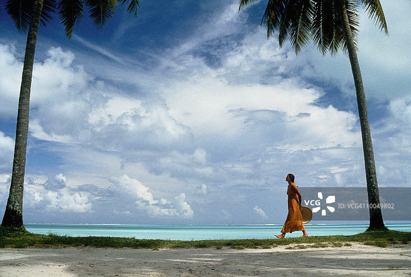 女人在南太平洋的两棵棕榈树间行走图片素材