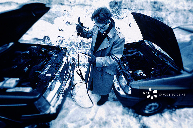 男人用电缆试图启动熄火的汽车图片素材