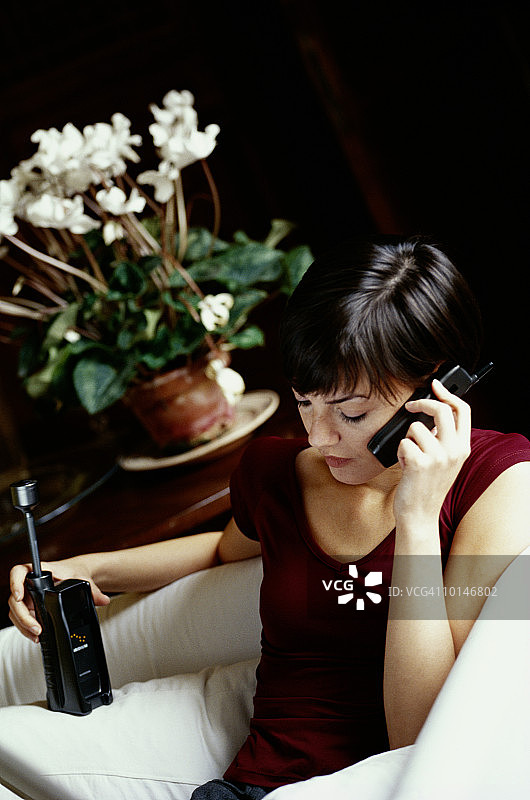 手持铱星移动电话的棕发女人图片素材