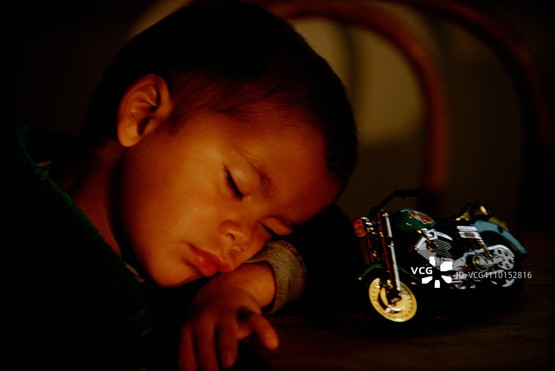 在厨房桌子上睡着的4岁男孩图片素材