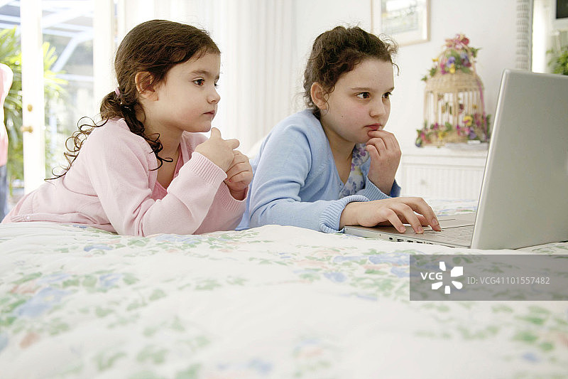 姐妹在家里一起使用笔记本电脑图片素材