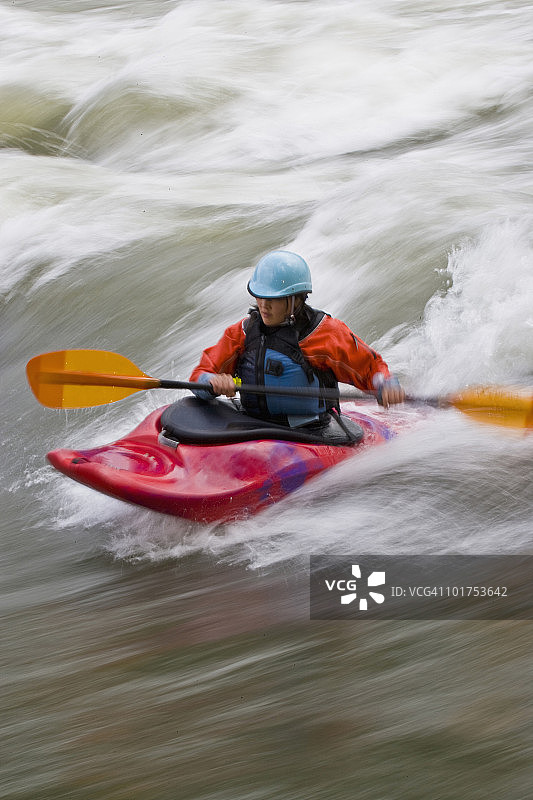 一位年轻的亚裔女子在加拿大不列颠哥伦比亚省东库特尼地区的麋鹿河上玩白浪皮划艇冲浪图片素材