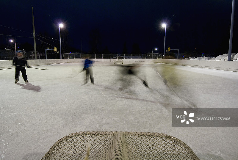 一家人在阿拉斯加州安克雷奇当地小学的溜冰场上玩冰球图片素材