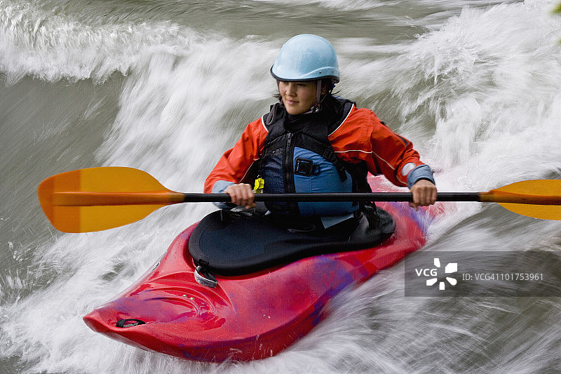 一位年轻的亚裔女子在加拿大不列颠哥伦比亚省东库特尼地区的麋鹿河上玩白浪皮划艇冲浪图片素材
