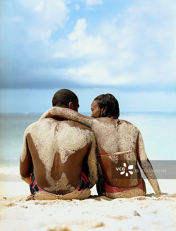 年轻夫妇坐在沙滩上，背影图片素材