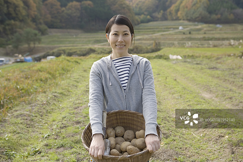 手提一篮土豆微笑的日本女人图片素材