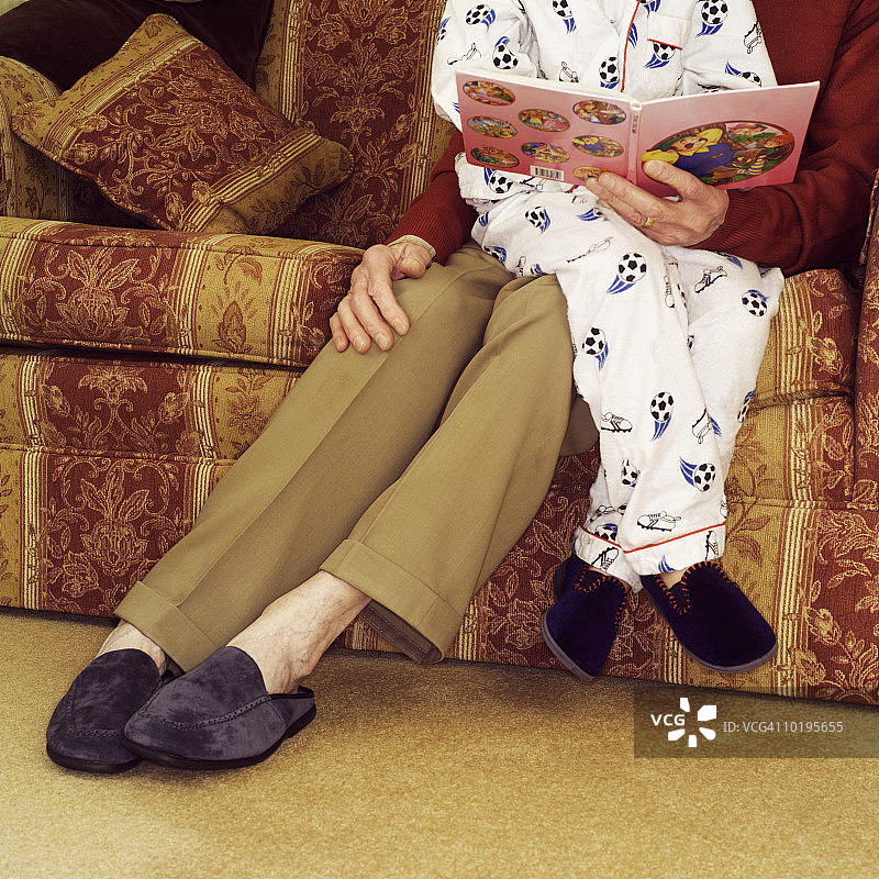 男孩（5-7岁）坐在祖母的腿上，读故事书，低角度图片素材