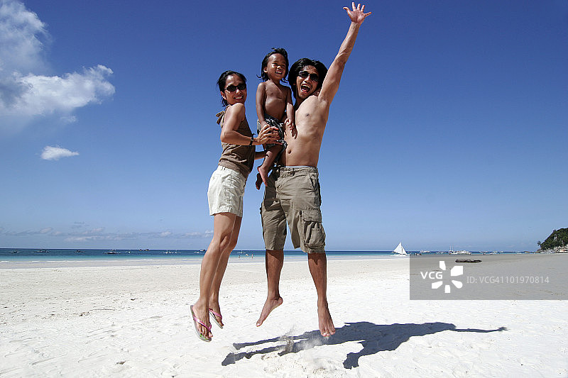 父母和儿子在海滩跳跃图片素材