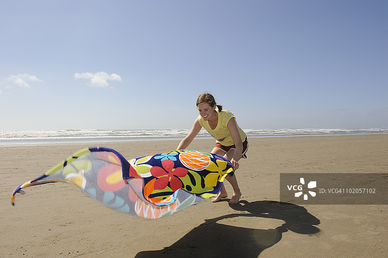 女子在沙滩上铺开毛巾图片素材