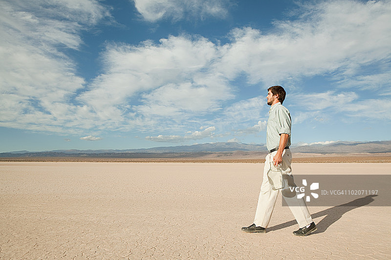 在沙漠景观中拿着一瓶水的男子图片素材