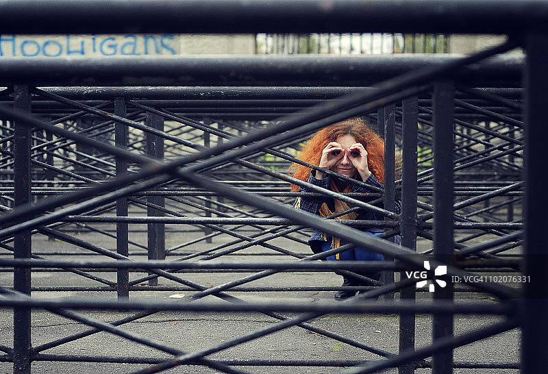 乌克兰敖德萨：躲在铁栅栏后面的红发女子图片素材
