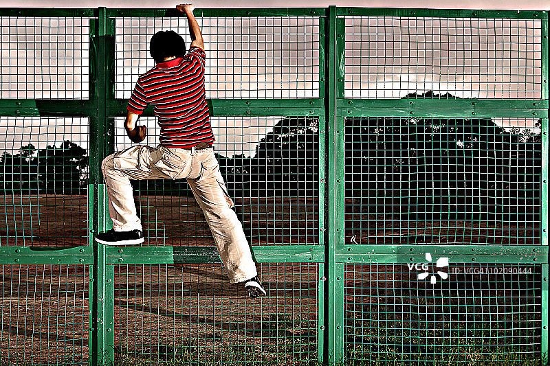 男人攀爬链条围栏图片素材