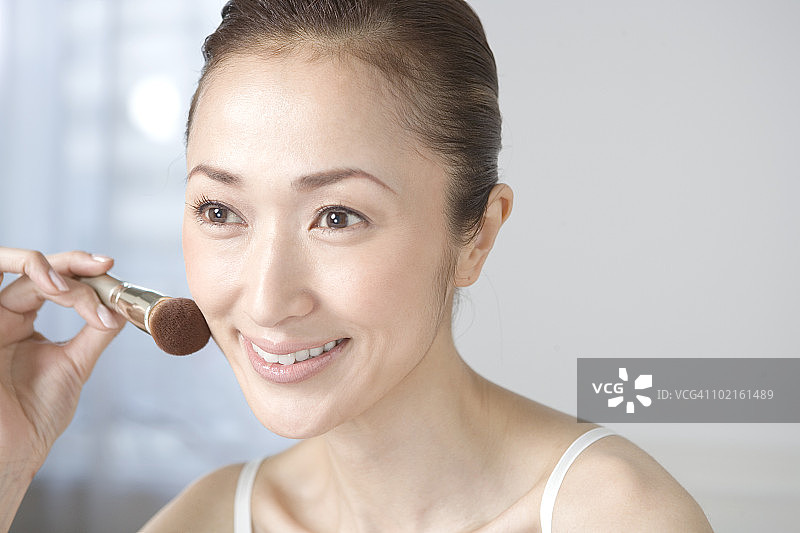 中年妇女用刷子在脸上扑粉图片素材