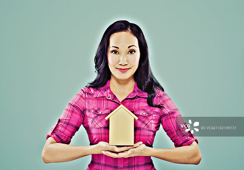 拿着玩具房子的微笑亚洲女人图片素材
