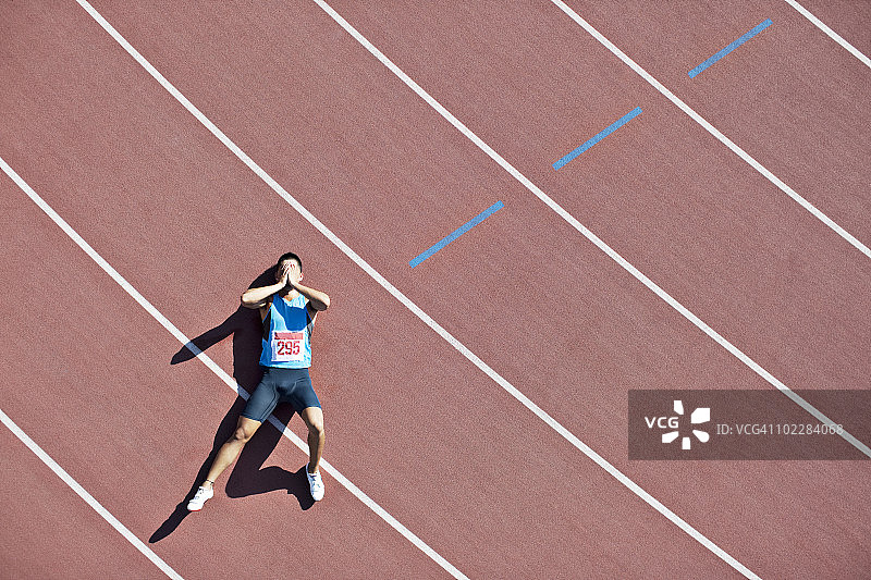 疲惫的跑步者躺在跑道上图片素材