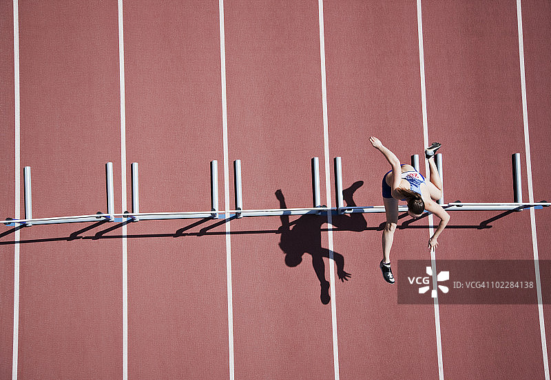 跑步者在赛道上跳跨栏图片素材
