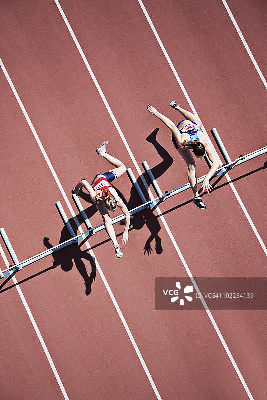 跑步者在赛道上跨越障碍图片素材