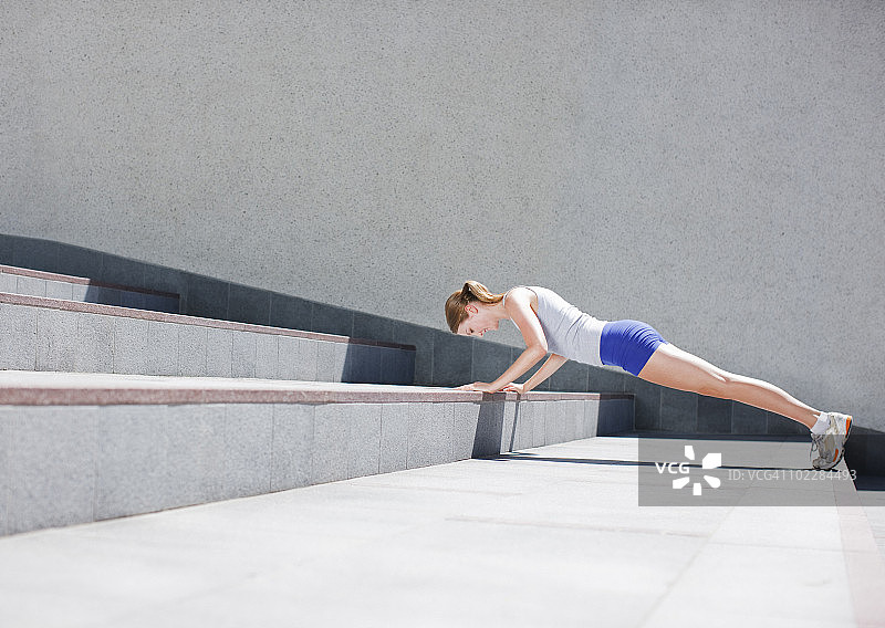在城市楼梯上做俯卧撑的女人图片素材