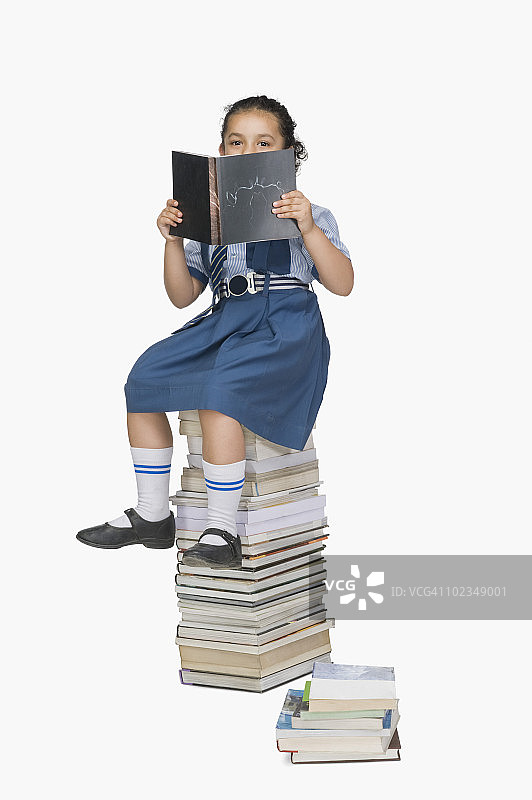 坐在书堆上读书的女学生图片素材