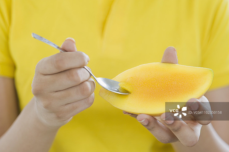 女人用勺子吃芒果图片素材