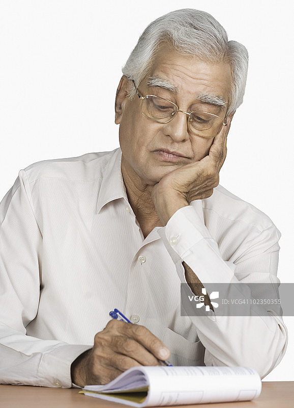 年长的男人在笔记本上写作的特写镜头图片素材