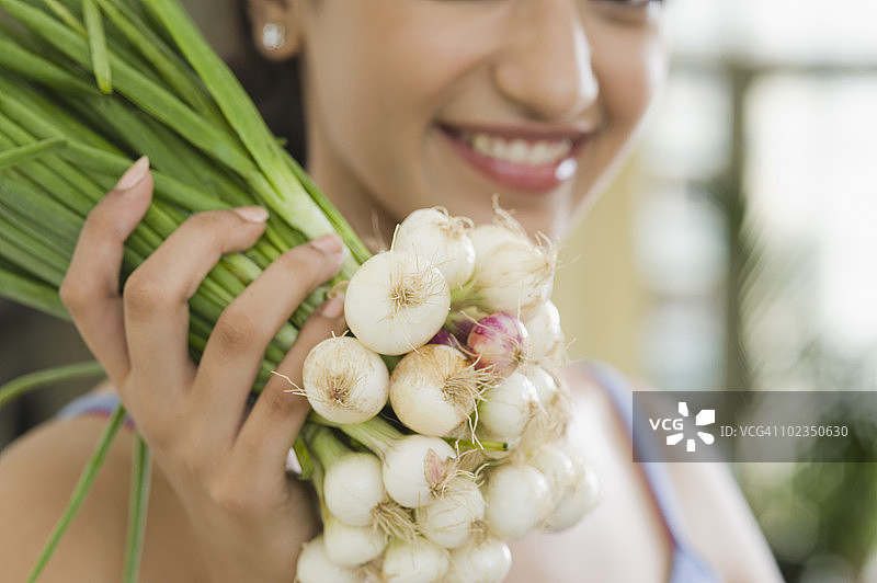 拿着一把葱并微笑的女人图片素材