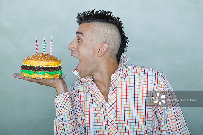 留着莫霍克发型的男人拿着汉堡生日蛋糕图片素材