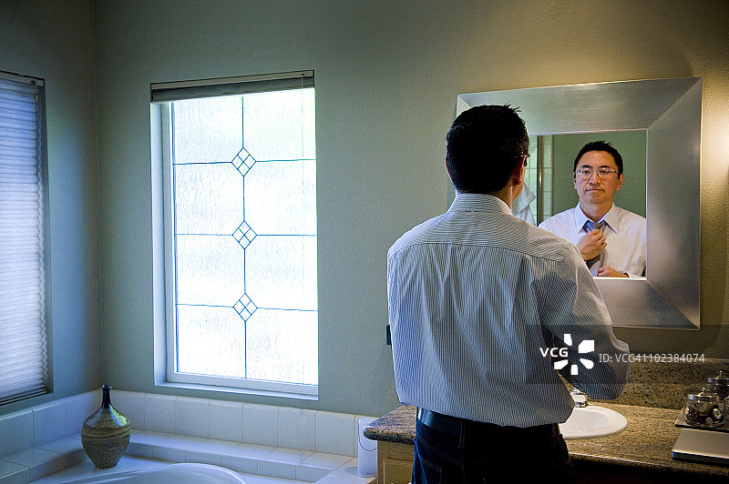在浴室镜子前穿衣的男人图片素材