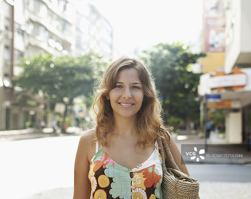 年轻女子提着购物袋对着镜头微笑图片素材