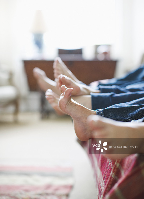 一家人躺在床上，侧面视角，聚焦脚部图片素材