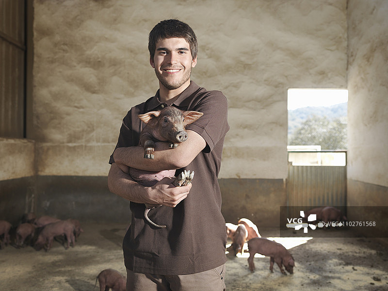 男人在围栏里抱着小猪图片素材